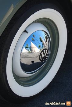 a car's side view mirror is reflecting the palm trees and sky in it