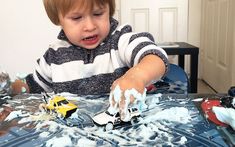 a little boy that is sitting at a table with some toys in front of him