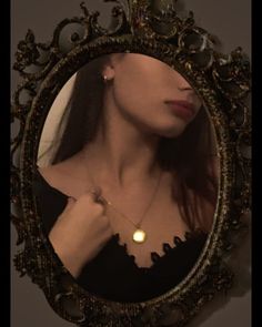 a woman in a black dress is looking at her reflection in a gold framed mirror