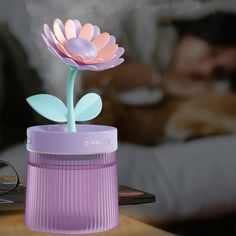 a pink flower in a purple vase on a table