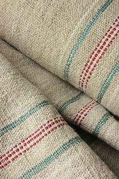 a close up view of the fabric on top of a bed sheet with red and green stripes