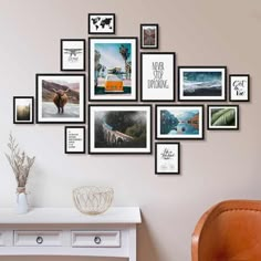 a bunch of pictures hanging on the wall next to a table with a vase and chair