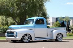 an old blue and white truck parked on the street