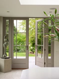 an open door leading to a patio with a statue in the foreground and a garden behind it