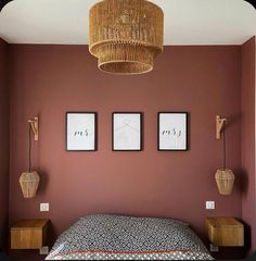 a bedroom with red walls and two pictures hanging on the wall above the headboard