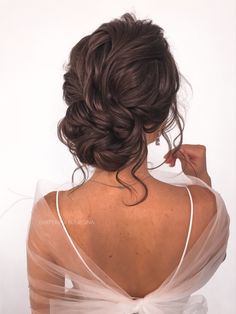 a woman with her back to the camera, wearing a white dress and braided hair