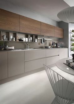 a modern kitchen with white and wood cabinets, counter tops, and an oval dining table