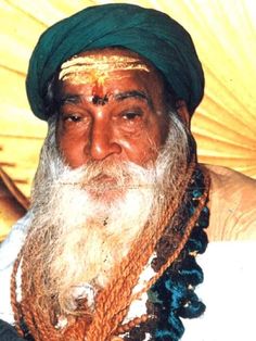 an old man with long white beard and green turban, sitting in front of a yellow umbrella