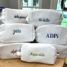 six personalized white wash bags sitting on top of a wooden table in front of a window