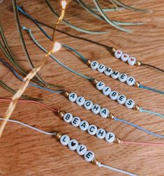 four beaded name bracelets sitting on top of a wooden table