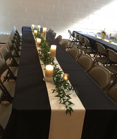 a long table is set with candles and black cloths for an event or conference