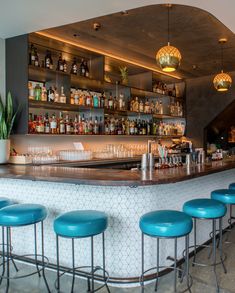 a bar with blue stools and bottles on the shelves