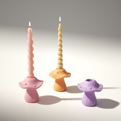 three candles with different shapes and sizes in the shape of mushroomes, on a white background