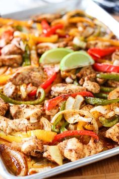 a casserole dish with chicken, peppers, onions and limes on it