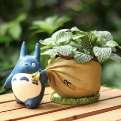 a small figurine sitting next to a potted plant on a wooden table