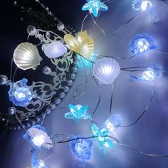 some lights that are on the side of a wall with shells and flowers in them