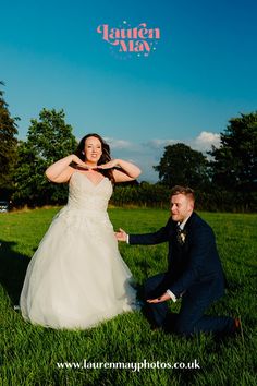 a man kneeling down next to a woman in a wedding dress on top of a grass covered field