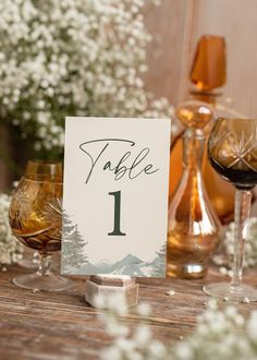 a table number with wine glasses and flowers in the background