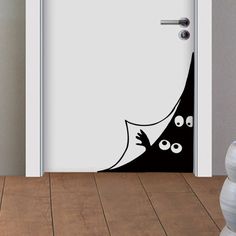 an open door with a black and white design on the front, behind which is a cat's head