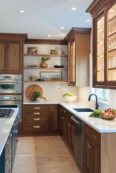 a kitchen filled with lots of wooden cabinets and white counter tops next to a stove top oven