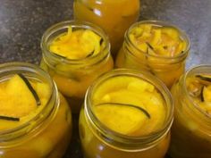 several jars filled with yellow food sitting on top of a granite countertop next to each other