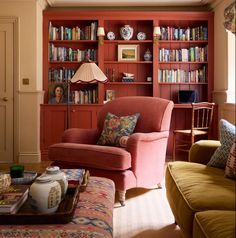 a living room filled with lots of furniture and bookshelves covered in red bookcases