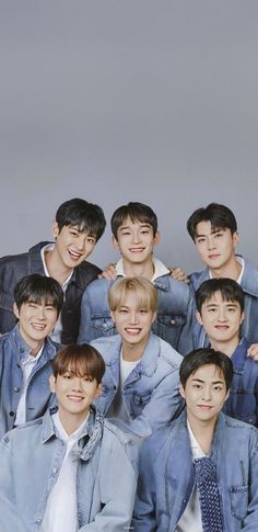 a group of young men standing next to each other in front of a gray background