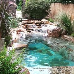 a pool with rocks and water features a waterfall