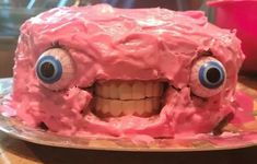 a close up of a cake on a plate with googly eyes and pink frosting