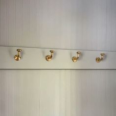 four brass handles on the wall in a bathroom