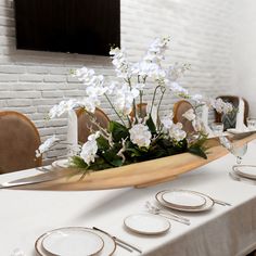 the table is set with white flowers and place settings