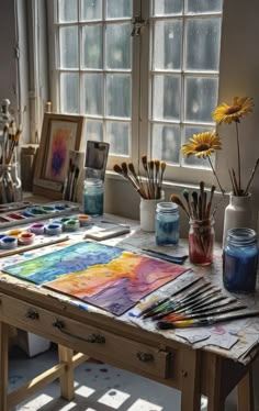 the sun shines through the window onto an artist's desk with watercolor paints and brushes