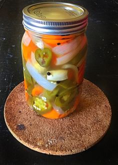 a jar filled with pickles sitting on top of a cork coaster