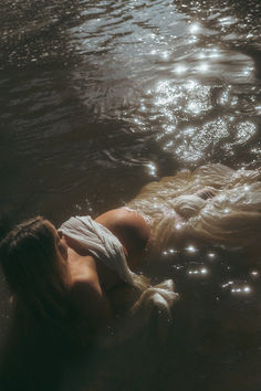 a woman is floating in the water with her head on her back and eyes closed