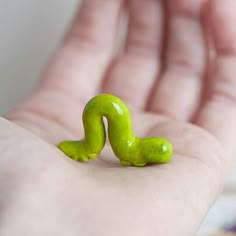 a green toy worm sitting on top of a persons hand