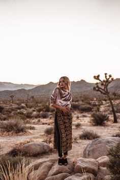 a woman standing on top of a rock in the desert