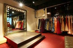 a dressing room with clothes on racks and a large mirror