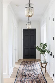 a hallway with a black door and rug on the floor next to an entryway