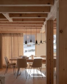 a dining room table and chairs with wooden beams on the ceiling in front of a sliding glass door