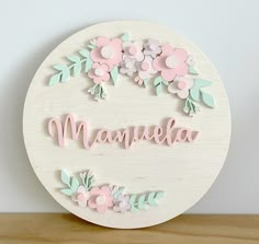 a wooden sign with flowers and the word mauvela written in pink on it