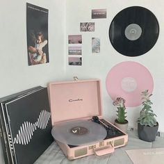 a record player sitting on top of a table next to a plant and vinyl records