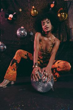 a woman is sitting on the floor with her legs crossed and holding a disco ball