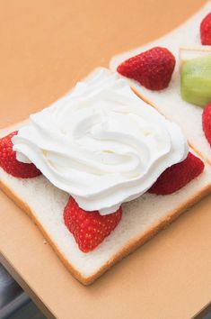 two slices of bread with whipped cream and strawberries on top, sitting on a table