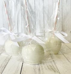 three white apples wrapped in plastic and tied with ribbons