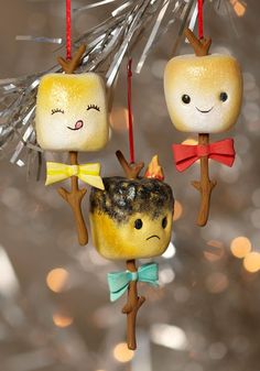 three ornaments hanging from a christmas tree decorated with little faces and bows on their heads