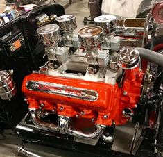 an orange engine sitting on top of a black car with chrome trim and silver piping