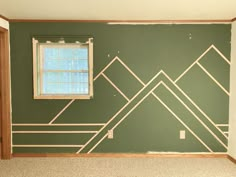 an empty room with green walls and gold lines painted on the wall, along with a window