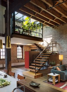 a living room filled with furniture and a spiral stair case next to a brick wall