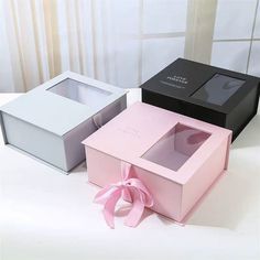 three open boxes with pink bows on the top and one black box with white inside