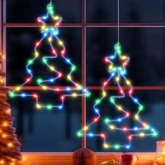 a decorated christmas tree in front of a window with lights on it and presents under the windowsill